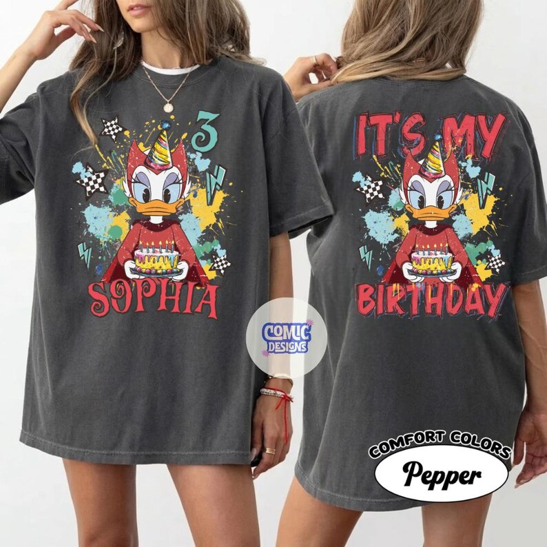 Puede incluir: Camiseta gris oscuro con un pato de dibujos animados sosteniendo un pastel de cumplea&ntilde;os. La parte delantera de la camiseta dice "Sophia" y "3". La parte trasera de la camiseta dice "It's My Birthday". La camiseta tiene un aspecto vintage.