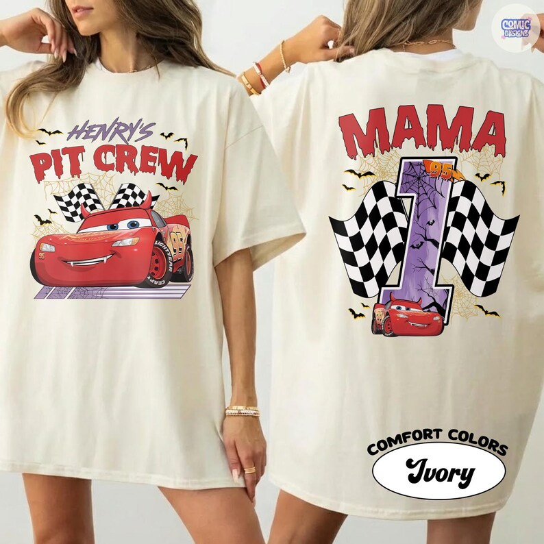 Puede incluir: Una camiseta color marfil con un gr&aacute;fico de coche de carreras rojo y el texto Henry's Pit Crew en el frente. La parte posterior muestra la palabra Mama sobre un gran n&uacute;mero uno morado, un coche de carreras rojo y banderas a cuadros con telara&ntilde;as.