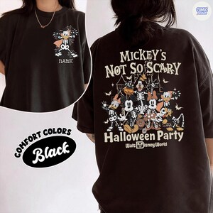 Puede incluir: Camiseta negra con un dise&ntilde;o tem&aacute;tico de Halloween. La parte delantera muestra un personaje de dibujos animados con un disfraz de esqueleto con el texto "NAME". La parte trasera de la camiseta dice "Mickey's Not So Scary Halloween Party" con personajes de Disney.