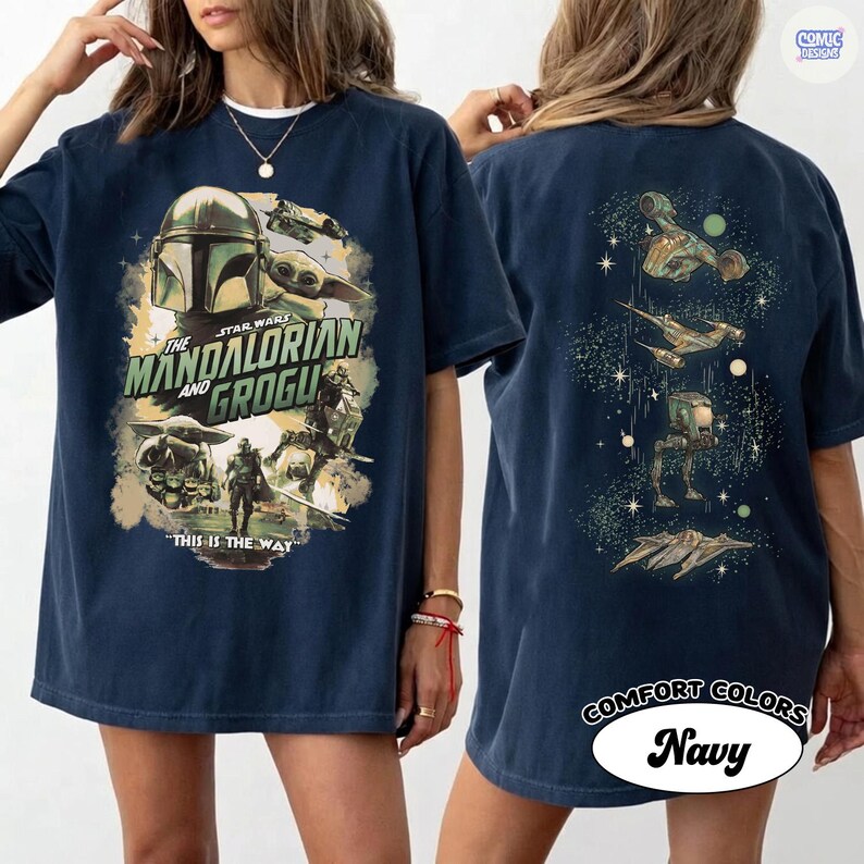 Op de afbeelding: Marineblauwe t-shirt met een afbeelding uit de serie The Mandalorian. De voorkant toont de Mandalorian en Grogu, met de tekst "The Mandalorian and Grogu" en "This is the Way". De achterkant toont ruimteschepen.