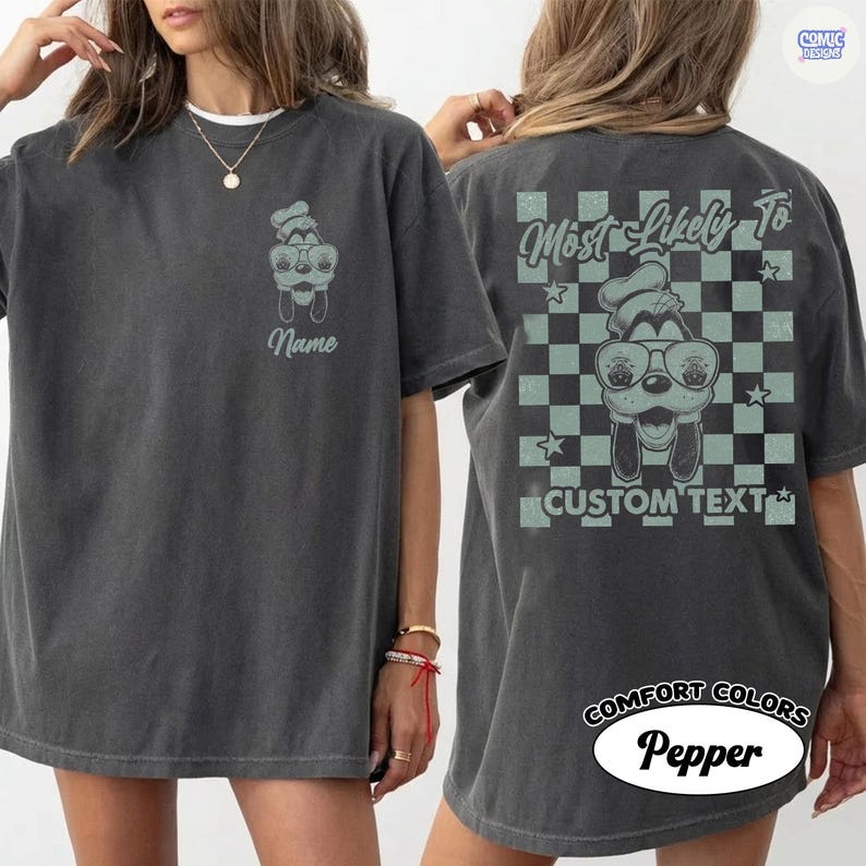 May include: Dark grey t-shirt with a cartoon dog wearing sunglasses and a chef's hat. The front of the shirt has the word "Name" below the dog graphic. The back of the shirt features the text "Most Likely To" above the dog graphic and "Custom Text" below it.