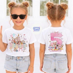 May include: White t-shirt with a colorful Disney-themed design on the front, including a castle, balloons, and characters. The text "Birthday Girl" is also visible. The back of the shirt features a large pink number 5 and the name "Charlotte".