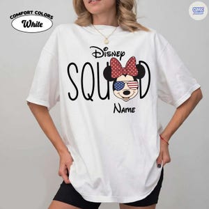 May include: White Comfort Colors t-shirt with a Disney Squad design. The design features Minnie Mouse with a red polka dot bow and sunglasses with an American flag design. The word "Disney" is above the word "Squad". The word "Name" is below the Minnie Mouse graphic.