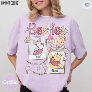 Puede incluir: Camiseta color orqu&iacute;dea con la palabra "Besties" en escritura rosa. La camiseta presenta ilustraciones de Piglet y Winnie the Pooh, con el texto "Piglet" y "Pooh" debajo de sus im&aacute;genes. La camiseta tambi&eacute;n tiene el texto "Best Friends Forever".