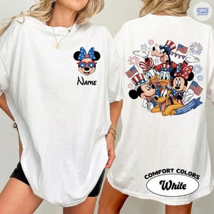 May include: White t-shirt featuring Minnie Mouse in patriotic sunglasses and bow, with the word "Name" below. The back of the shirt displays a group of Disney characters with American flags and fireworks. The text "America 250th USA Anniversary 1776-2026" is on a banner.