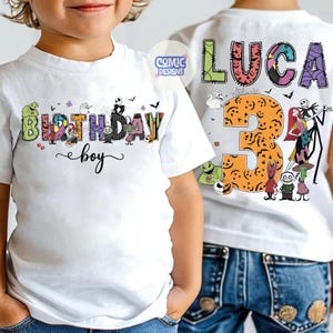 May include: A white t-shirt featuring a graphic print with the text BIRTHDAY boy and the name LUCA with the number 3. The design includes colorful, patterned letters and various animated characters from a movie, including skeletons and ghosts.