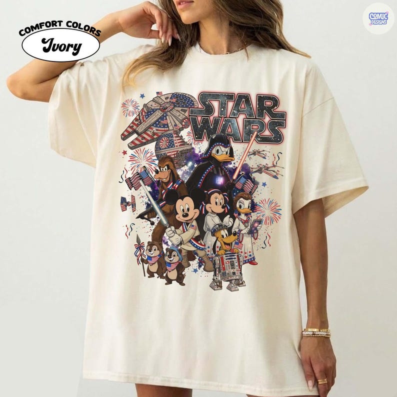 May include: Ivory-colored t-shirt featuring a Star Wars graphic with various Disney characters, fireworks, and an American flag theme. The shirt includes the text "STAR WARS" and "COMFORT COLORS".