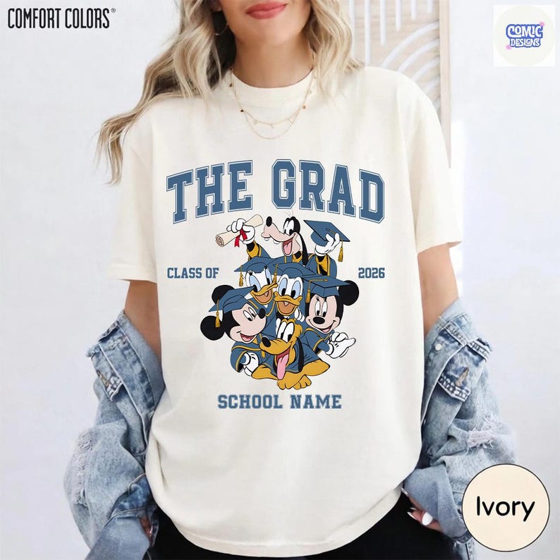 Puede incluir: Camiseta color marfil con la frase azul "THE GRAD", "CLASS OF 2026" y "SCHOOL NAME". Presenta un dise&ntilde;o de personajes de Disney con atuendo de graduaci&oacute;n. La camiseta es de Comfort Colors.