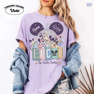 May include: Violet Comfort Colors t-shirt featuring a Disney-themed design. The design includes Mickey Mouse, Minnie Mouse, Donald Duck, and other characters, with the text "EPCOT" and "The Smith Family". The shirt also has the text "NAME" and "2026".