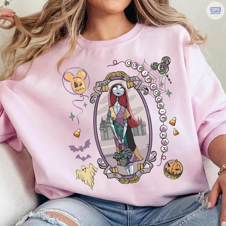 Puede incluir: Una sudadera de cuello redondo rosa claro con un marco ovalado central que contiene un gr&aacute;fico de Sally de Pesadilla antes de Navidad. El dise&ntilde;o incluye el texto Oogie Boogie Bash, un globo, un fantasma, murci&eacute;lagos, caramelos y una calabaza.