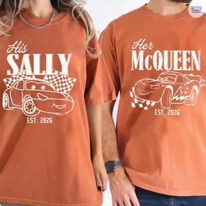 May include: Two burnt orange t-shirts with white graphics. One says "His SALLY" with a car illustration and "EST. 2026". The other says "Her McQUEEN" with a car illustration and "EST. 2026".