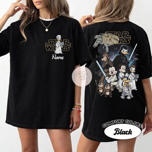 May include: Black t-shirt featuring a Star Wars-themed design. The front displays a cartoon character with the Star Wars logo and the word "Name". The back showcases various characters, the Star Wars logo, and the text "Comfort Colors Black".