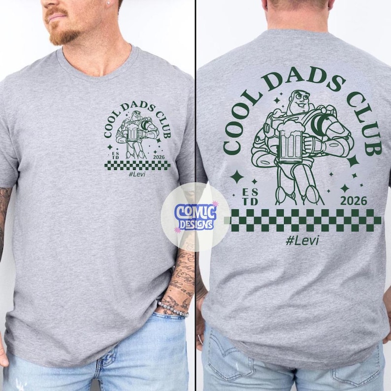 May include: A light gray t-shirt with a green graphic of Buzz Lightyear holding a beer mug, with the text "COOL DADS CLUB" and "#Levi". The back of the shirt also features the same design. The shirt has a checkered pattern at the bottom.