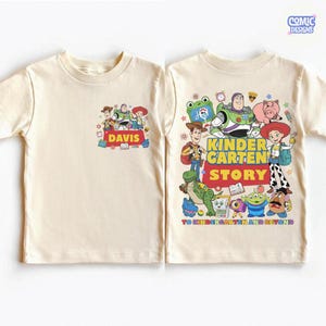 May include: A cream-colored t-shirt featuring a small chest graphic of Toy Story characters with the name DAVIS and a large back graphic of Toy Story characters with the text KINDERGARTEN STORY TO KINDERGARTEN AND BEYOND in colorful letters.