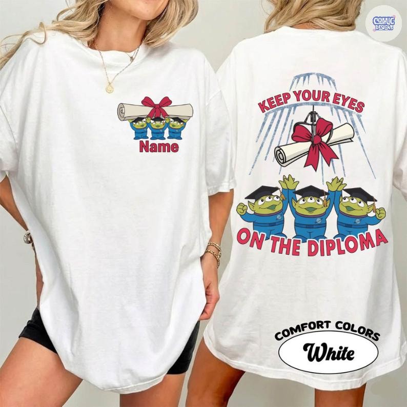 May include: White t-shirt featuring a graduation-themed design. The front displays three green aliens holding a diploma with a red bow, with the word "Name" below. The back has the text "KEEP YOUR EYES ON THE DIPLOMA" and the Comfort Colors logo.
