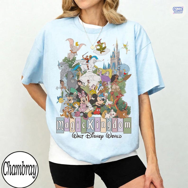 Puede incluir: Camiseta azul claro con un gr&aacute;fico colorido de personajes de Disney, incluyendo Mickey Mouse, Dumbo y Peter Pan. El texto "Magic Kingdom Walt Disney World" se muestra debajo. La camiseta tiene mangas cortas y cuello redondo.