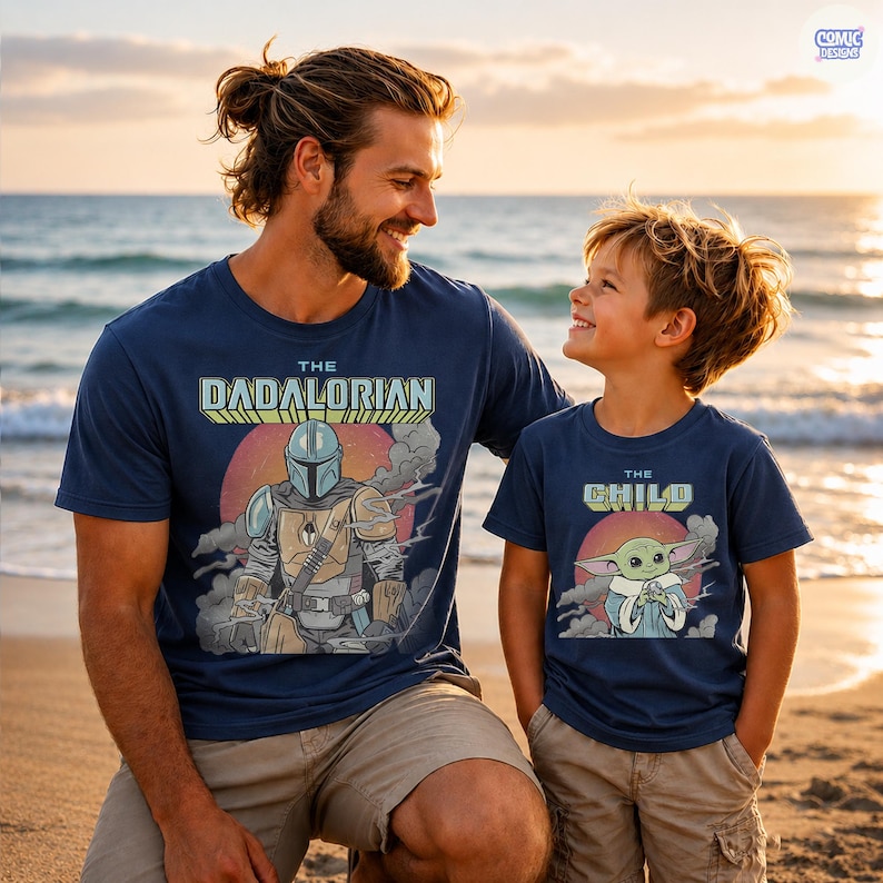 Puede incluir: Camisetas azul marino con gr&aacute;ficos a juego. Una camiseta dice "The Dadalorian" con un dise&ntilde;o mandaloriano, y la otra dice "The Child" con una imagen de Baby Yoda. Las camisetas las llevan un padre y un hijo en la playa.