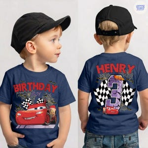 Puede incluir: Una camiseta azul marino con un gr&aacute;fico de coche de carreras rojo, patrones de telara&ntilde;a y el texto "BIRTHDAY BOY" en el frente. La parte posterior muestra el nombre "HENRY" sobre un n&uacute;mero "3" grande y un dise&ntilde;o de bandera a cuadros.