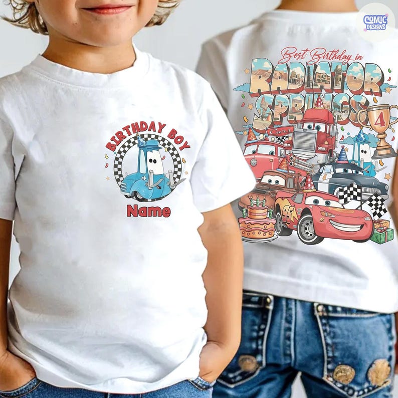 May include: White t-shirt featuring a blue cartoon car with the text "BIRTHDAY BOY" and "Name" in red. The back of the shirt displays a colorful graphic with cars, the text "Best Birthday in Radiator Springs", and a trophy.