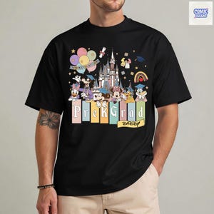 May include: Black t-shirt featuring a colorful graphic of Disney characters, a castle, balloons, and the text "Prek Grad Daddy." The design includes graduation caps and the word "Congratulations."