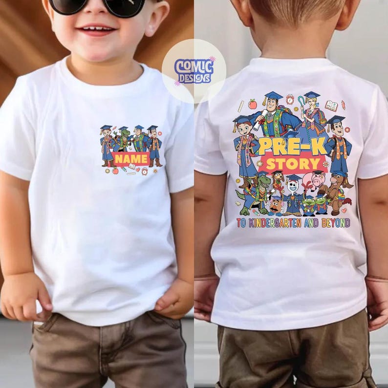 May include: White t-shirt with a colorful graphic featuring cartoon characters and the text "PRE-K STORY" on the back. The front of the shirt has a smaller graphic with the word "NAME" and a space for personalization. The shirt is for children.