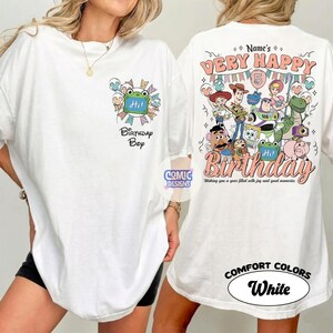 May include: White t-shirt with a colorful graphic design. The front features a frog with the text "Hi!" and "Birthday Bop." The back displays "Very Happy 5th Birthday" with cartoon characters. The shirt is labeled "Comfort Colors White."