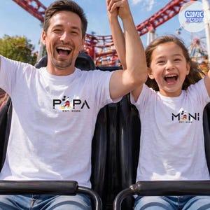 May include: White t-shirts with black text and a Mickey Mouse graphic. The shirt on the left says "PAPA EST. 2026" and the shirt on the right says "MINI EST. 2026". The people are on a roller coaster.