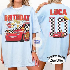 May include: Light blue t-shirts with a Cars theme. The front features text "BIRTHDAY Boy" with a red race car. The back has the name "LUCA" and the number "10" with a checkered flag design. The shirts are labeled "COMFORT COLORS Light Blue".