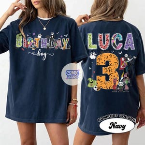 May include: A navy blue t-shirt featuring a front graphic with the text BIRTHDAY boy and a back graphic with the name LUCA, the number 3, and various animated characters from The Nightmare Before Christmas in colorful, patterned lettering.