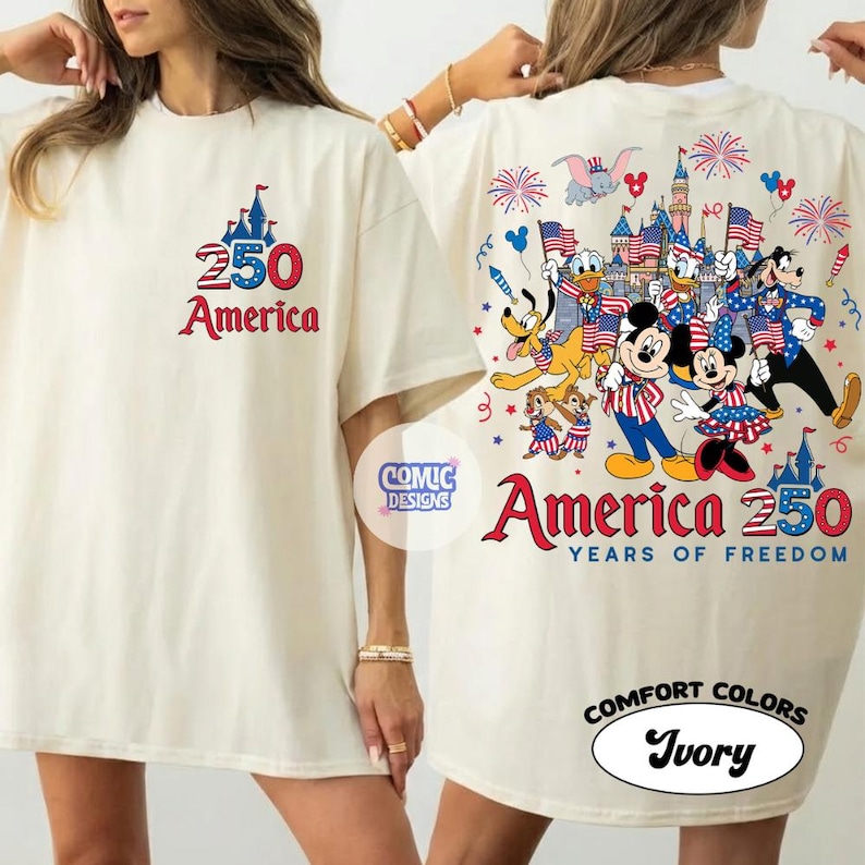 以下が含まれることがあります： アイボリー色のTシャツ。前面には赤と青で「250 America」と書かれています。背面には、旗と花火を持つディズニーのキャラクターと「America 250 Years of Freedom」の文字が描かれています。