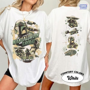 Puede incluir: Camiseta blanca con dise&ntilde;o de Star Wars. El frente muestra a The Mandalorian y Grogu, con el texto "THIS IS THE WAY". La parte trasera tiene m&aacute;s im&aacute;genes de Star Wars. La camiseta est&aacute; etiquetada como "COMFORT COLORS" y "White."
