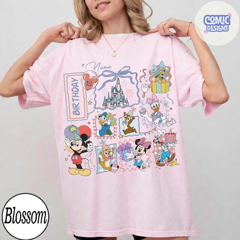 May include: A light pink t-shirt featuring a colorful Disney-themed birthday design. The design includes cartoon characters, a castle, and the word "Birthday". The shirt has short sleeves and a relaxed fit.