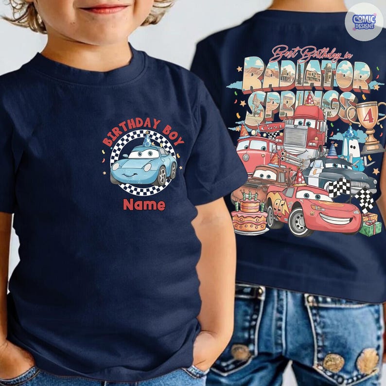 May include: Navy blue t-shirt featuring a cartoon car design with the text "Birthday Boy" and space for a name. The back of the shirt displays a colorful graphic of various car characters and the words "Best Birthday in Radiator Springs".