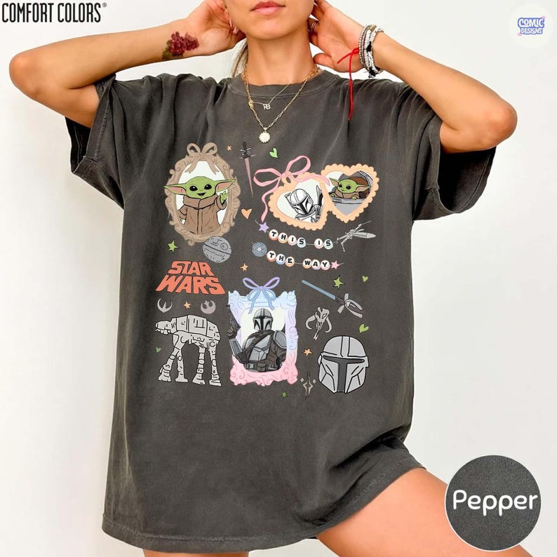 Puede incluir: Camiseta de color pimienta con gr&aacute;ficos de Star Wars. El dise&ntilde;o incluye im&aacute;genes de Grogu, el Mandaloriano y un caminante AT-AT. El texto "Star Wars" se muestra de forma destacada, junto con otros elementos decorativos.