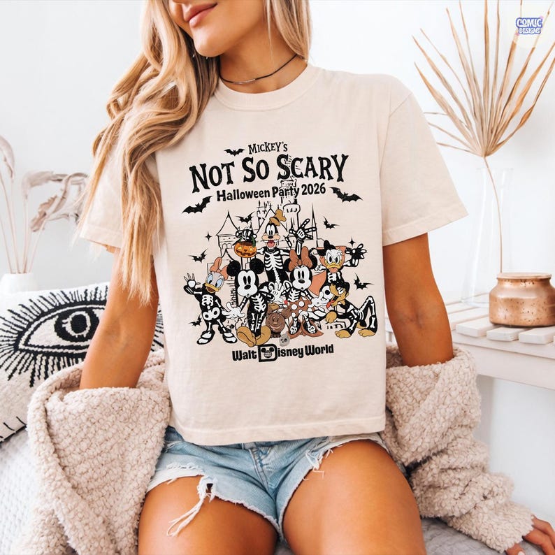 May include: Cream-colored t-shirt featuring a Halloween-themed graphic. The design includes the text "Mickey's Not So Scary Halloween Party 2026" with bats and cartoon characters. The Walt Disney World logo is at the bottom.