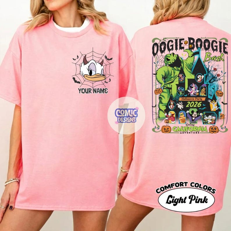 May include: Light pink t-shirt with a graphic of Daisy Duck in a spiderweb with the text "YOUR NAME" on the front. The back features a colorful design with the text "Oogie Boogie Bash" and "Halloween Party 2026".