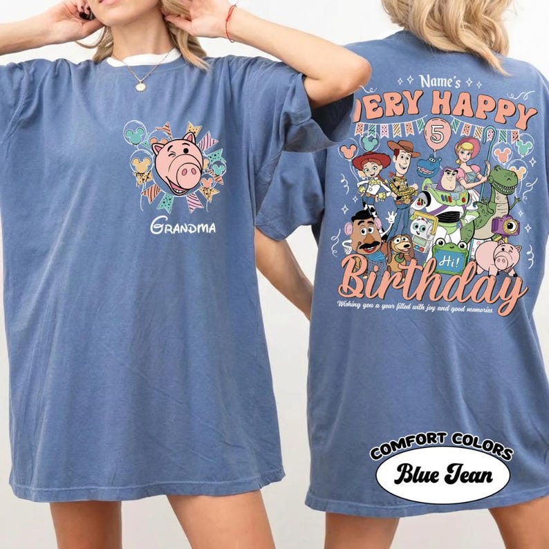 May include: Blue jean Comfort Colors t-shirt with a graphic of a pig and the word "Grandma" on the front. The back features a "Very Happy Birthday" design with cartoon characters and the text "Wishing you a year filled with joy and good memories."