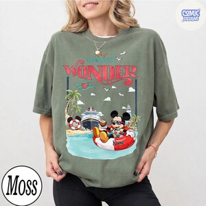 Puede incluir: Camiseta verde oliva con un dise&ntilde;o de Mickey Mouse relaj&aacute;ndose en una boya roja y blanca, con el texto "Disney Wonder". El dise&ntilde;o incluye un crucero, palmeras y un arco&iacute;ris.