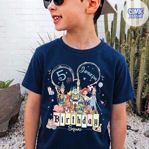 May include: Navy blue t-shirt featuring a colorful graphic of Toy Story characters. The shirt has the text "5 Joseph Birthday Squad" in a playful font. The design includes stars, balloons, and gift boxes, perfect for a birthday celebration.