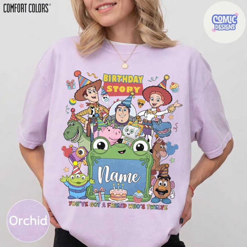 May include: A light purple t-shirt featuring a colorful graphic of Toy Story characters including Woody, Buzz Lightyear, Jessie, Rex, and others wearing party hats. The design includes the text Birthday Story and a green frame with the word Name.