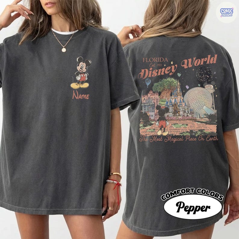K&ouml;nnte beinhalten: Dunkelgraues T-Shirt mit Mickey Mouse auf der Vorderseite und einer Disney World Grafik auf der R&uuml;ckseite. Auf der Vorderseite steht das Wort "Name" unter Mickey. Auf der R&uuml;ckseite steht der Text "Florida Disney World" und "The Most Magical Place On Earth".