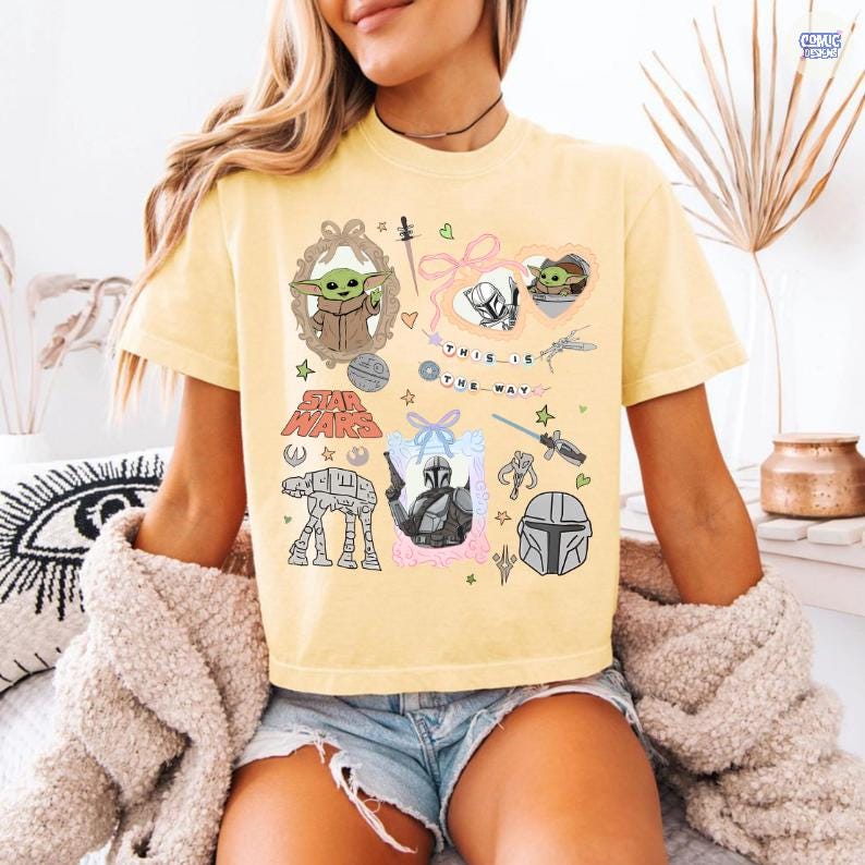 Puede incluir: Camiseta amarilla clara con gr&aacute;ficos tem&aacute;ticos de Star Wars. El dise&ntilde;o incluye im&aacute;genes de Grogu, el Mandaloriano y el texto "THIS IS THE WAY". La camiseta tiene cuello redondo y mangas cortas.