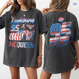 Puede incluir: Camiseta gris oscuro de Lightning McQueen con un gr&aacute;fico del personaje y el n&uacute;mero 95 en rojo, blanco y azul. La parte delantera de la camiseta muestra el texto "Lightning McQueen" y "Cars". La parte trasera tambi&eacute;n presenta el n&uacute;mero 95 y "Lightning McQueen".