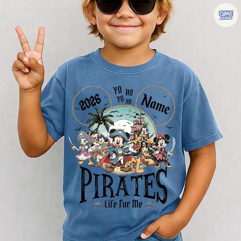 May include: Blue t-shirt featuring a pirate-themed graphic with Mickey Mouse and friends. The design includes the text "2026", "Yo Ho Ho", "Name", and "Pirates Life for Me". The shirt has a crew neck and short sleeves.