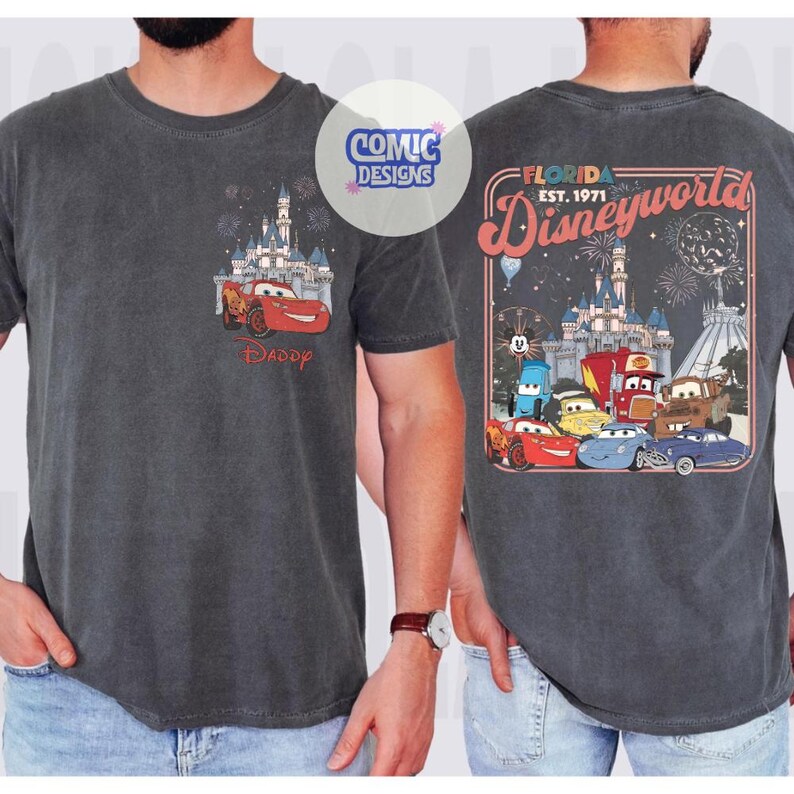 K&ouml;nnte beinhalten: Dunkelgraues T-Shirt mit einem Cars-Motiv. Auf der Vorderseite ist Lightning McQueen vor einem Schloss mit Feuerwerk und dem Wort "Daddy" zu sehen. Auf der R&uuml;ckseite befindet sich eine Disney World-Grafik mit Cars-Charakteren und dem Text "Florida Est. 1971".