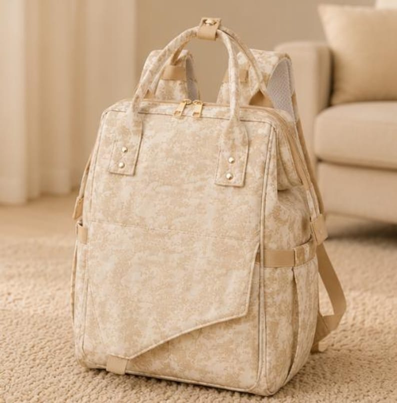 Peut inclure: Un sac &agrave; dos au motif marbr&eacute; beige et cr&egrave;me dot&eacute; d'un compartiment principal rectangulaire, d'une poche avant avec rabat diagonal, de deux poign&eacute;es sup&eacute;rieures, de fermetures &eacute;clair dor&eacute;es et de bretelles r&eacute;glables avec rembourrage en maille.