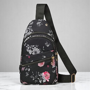 May include: A black floral print crossbody bag with a zippered pocket and adjustable strap.