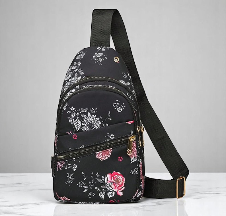 May include: A black floral print crossbody bag with a zippered pocket and adjustable strap.