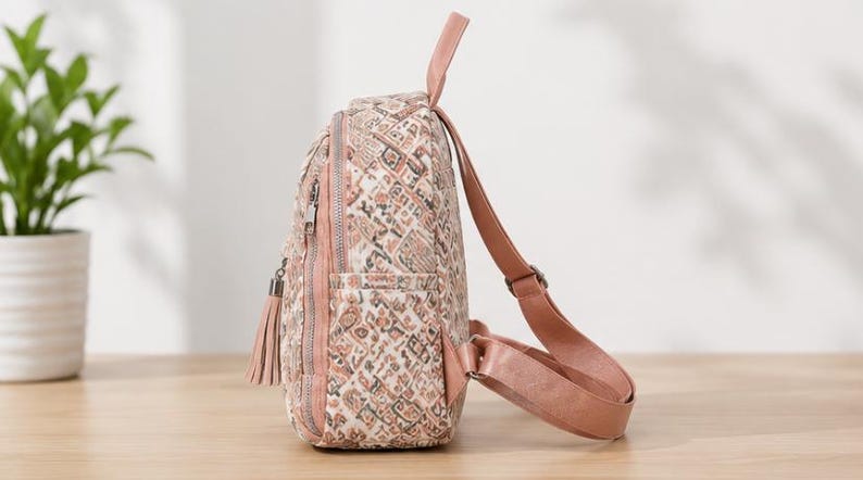 May include: A small backpack featuring a multi-colored geometric pattern in shades of pink, brown, and cream. The bag includes a top handle, adjustable pink shoulder straps, a side pocket, and a zippered front compartment with a decorative tassel.