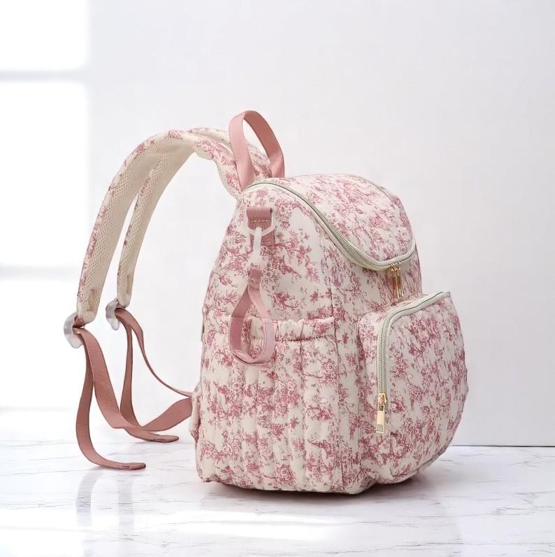 Puede incluir: Una mochila con estampado floral en crema y rosa. La mochila presenta un dise&ntilde;o acolchado, un bolsillo frontal con cremallera dorada y correas ajustables. Las correas y el asa son de color rosa liso. La mochila est&aacute; dise&ntilde;ada para el uso diario.